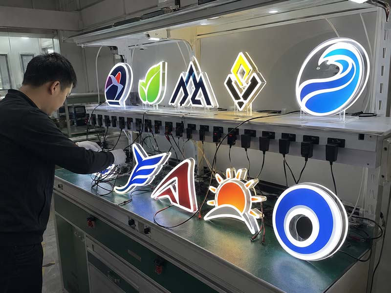 Acrylic LED logo signs undergoing lighting inspection and 72-hour aging test before shipment