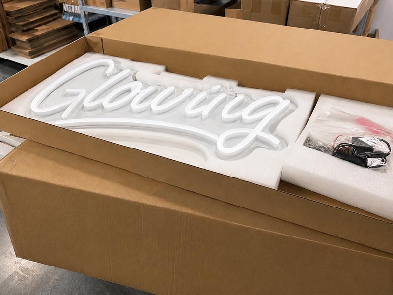 Neon sign packing in warehouse showing protective foam, carton, accessory bag, and transformer ready for export