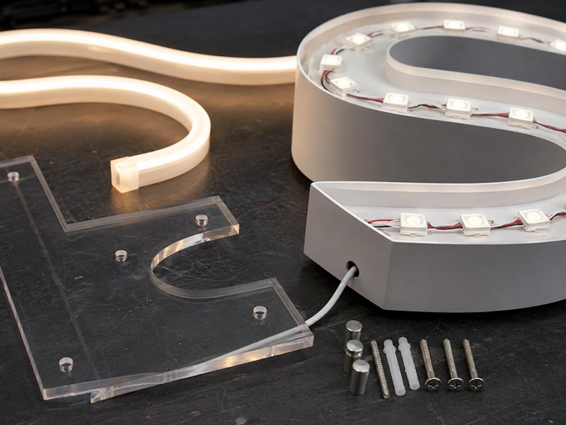 Close-up of LED sign product details including silicone neon tube, acrylic backing, LED modules, wire exit, and mounting hardware