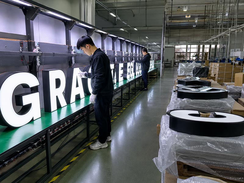 Iduoduo quality control staff testing illuminated channel letters for brightness, wiring stability, and pre-shipment inspection.
