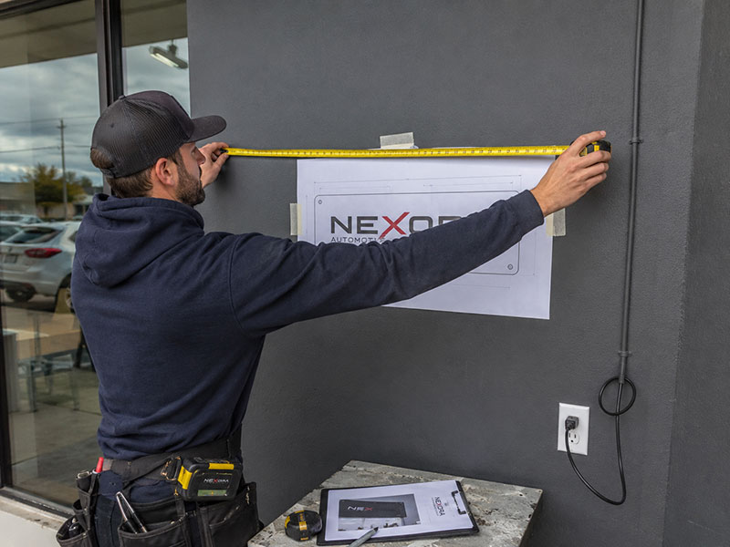Installer checking wall size, power position, and mounting details before custom LED sign production