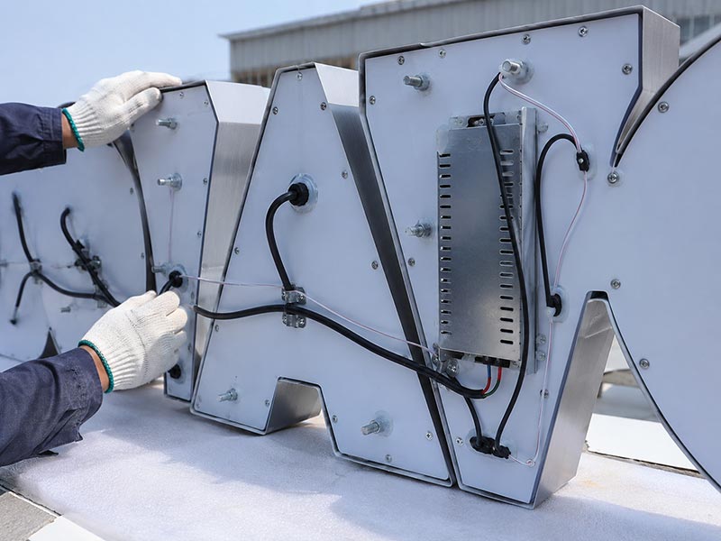 Back view of a custom LED sign showing LED layout, fixed wiring, power supply placement, and cable exit during quality checking