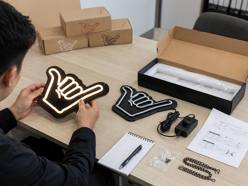 Factory staff carefully packing LED signs with foam, corner protection, and organized accessories for shipping.