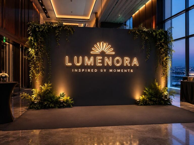 Custom illuminated sign installed on a modern event backdrop for branded photography