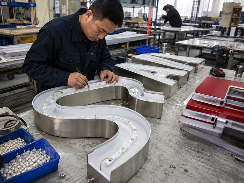 Factory worker fabricating LED channel letters with metal shells acrylic faces and LED modules