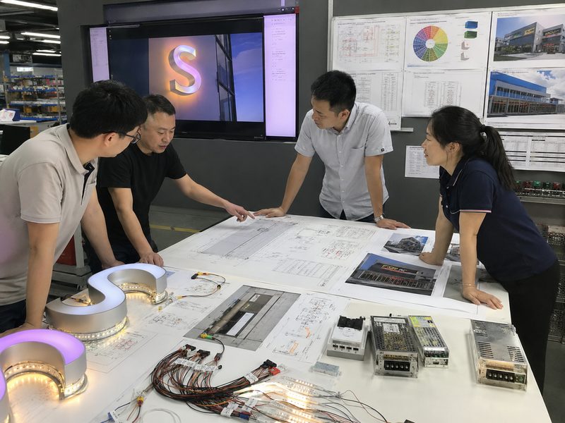 Engineers reviewing channel letter wiring, LED load, RGBW zones and lighting control specifications before production