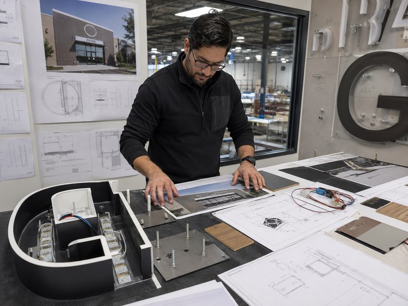 Sign engineer reviewing channel letter and backboard mounting options for a commercial storefront