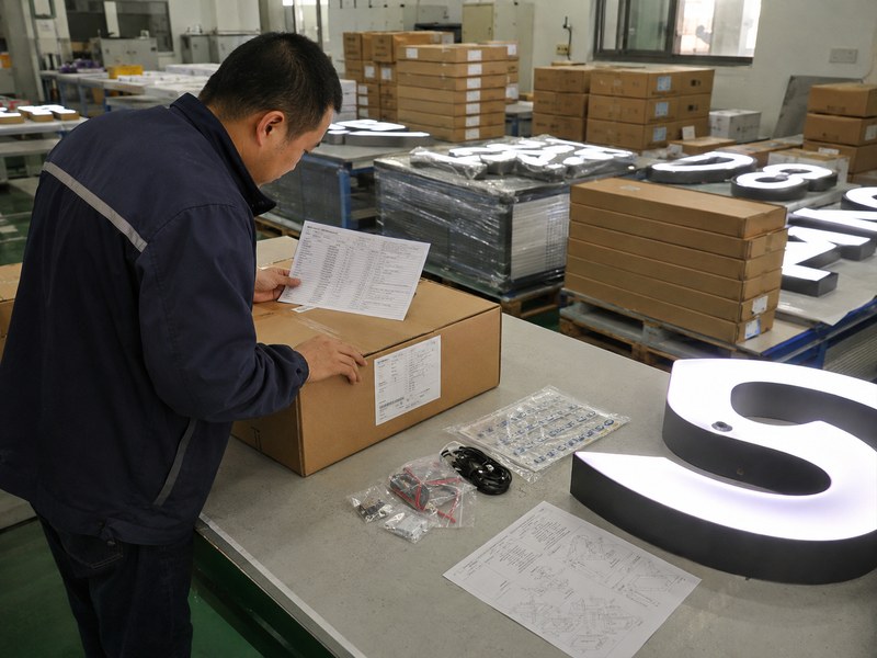 White-label sign manufacturer checking custom signs and neutral packaging before shipment