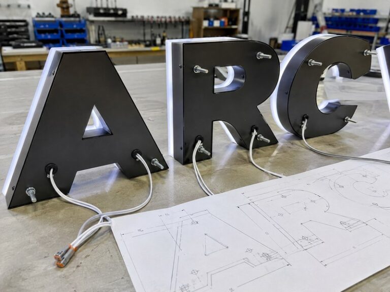 Custom channel letters with rear wire exit locations and mounting studs before installation